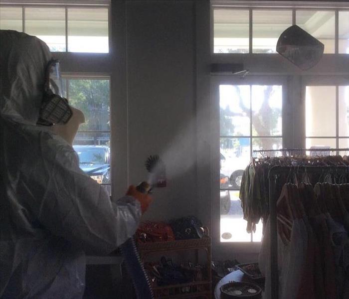 Man in PPE spraying inside a commercial retail store