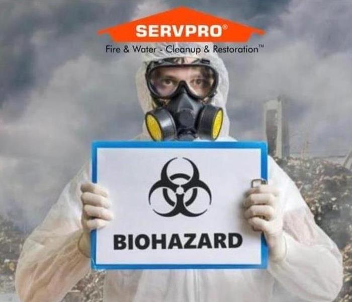 SERVPRO technician in full gear holding up a biohazard sign
